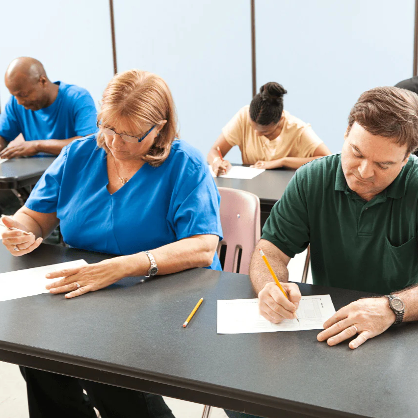 Adults writing an exam to represent the PAL and RPAL course and exam offered by Hawthorne Research, Training & Development.